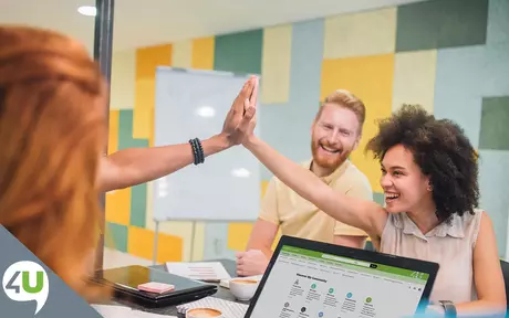 Laughing people high fiving in front of laptop